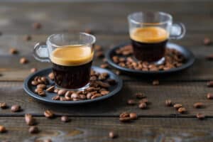 Two cups of espresso and coffee beans on a wooden table