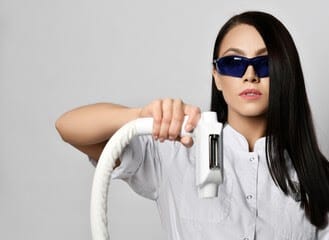 woman doctor cosmetologist holds equipment for laser hair removal