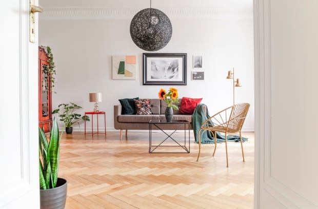 A spacious living room interior with eclectic furniture and a uniquely designed light hardwood floor.