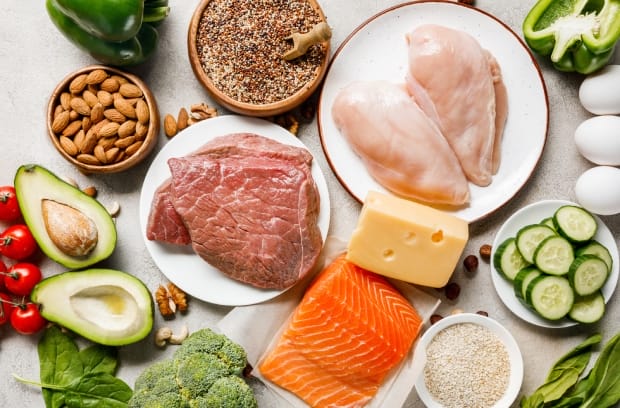 A healthy selection of low-carb foods including fish, chicken, and red meat, as well as greens and produce.