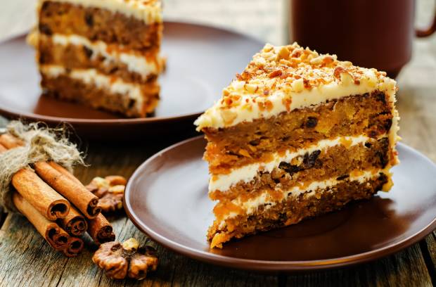 A delicious carrot cake with beautiful decorations, including white frosting and three layers of cake.