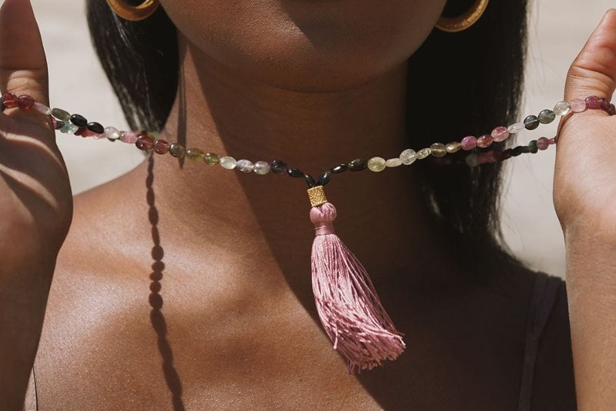Someone standing on a rock with special, spiritual jewelry on their toes and ankles. They're wearing a patterned skirt.