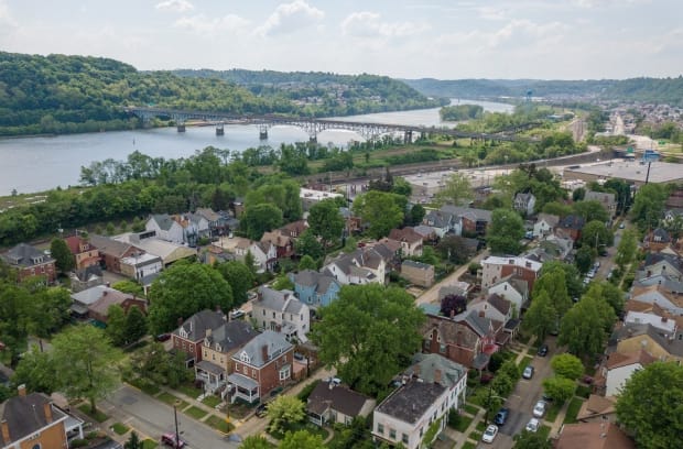 Aerial shot of many residential houses in the Aspinwall area of Pittsburgh. A river and bridge are visible in the background.