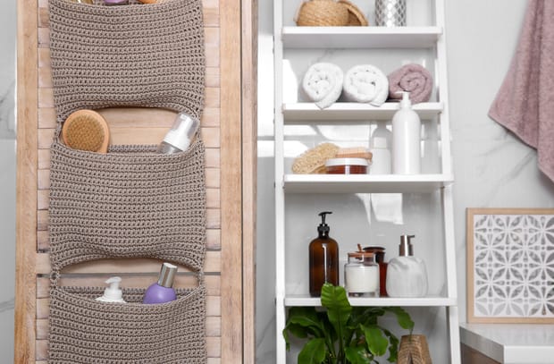 A stylish bathroom that has both ladder shelves and a hanging door organizer. Everything is neatly stored away.